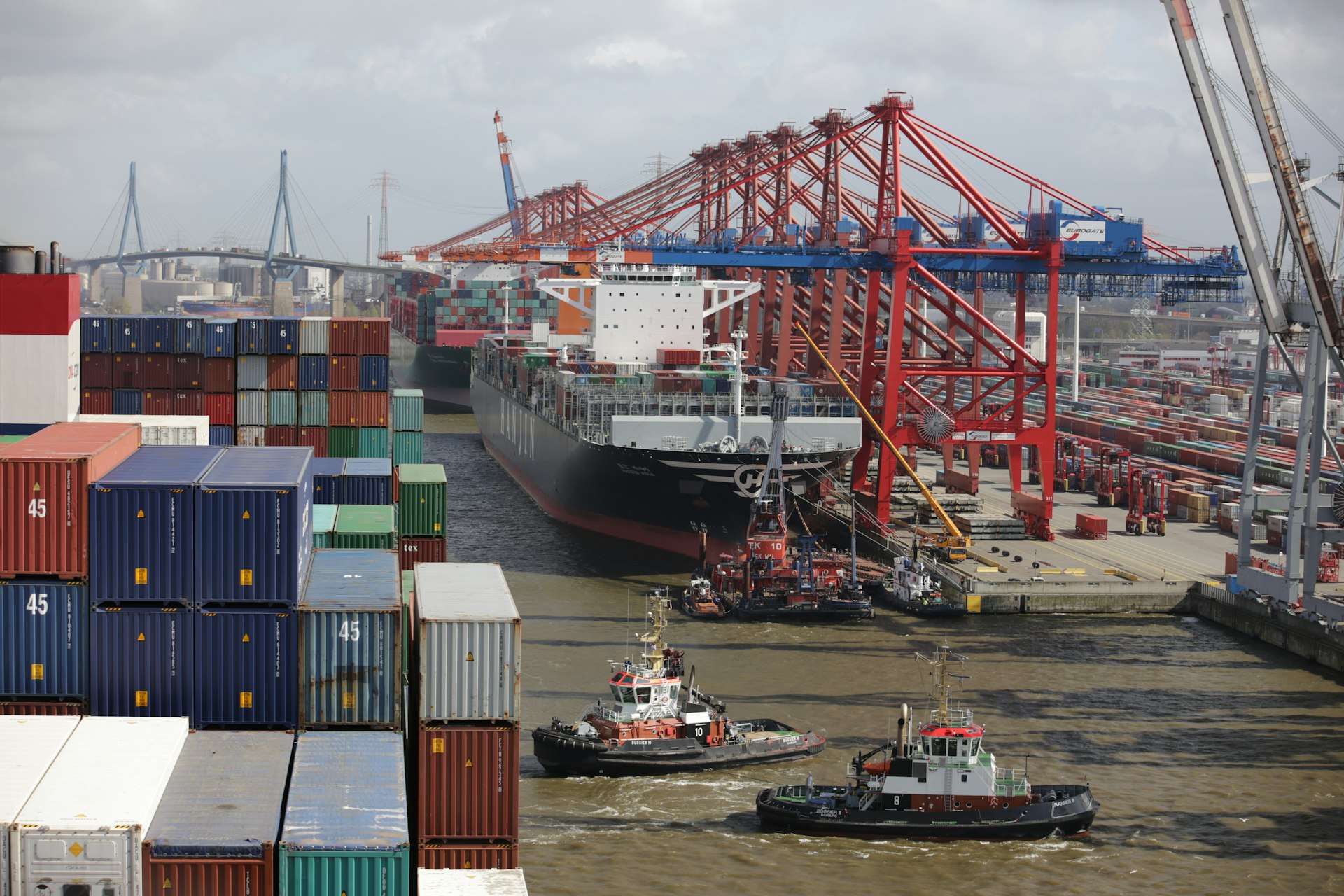 a tug boat in the water next to a large cargo ship